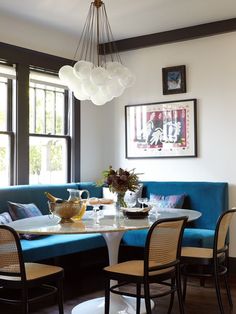 a table with four chairs around it in front of a blue couch and coffee pot