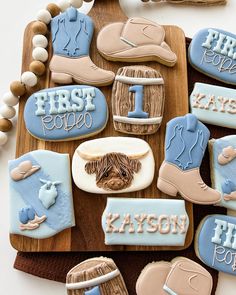 decorated cookies are arranged on a wooden platter with the words first rodeo and cowboy boots