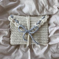 a crocheted piece of cloth with a bow on it laying on a bed