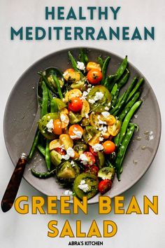 green bean salad with tomatoes and feta cheese in a bowl on top of a table