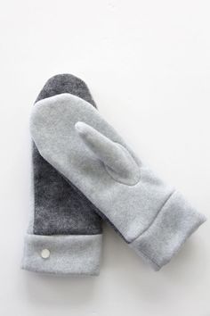 two gray mittens sitting next to each other on top of a white countertop