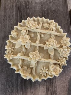 an elaborately carved dish with flowers on it sits on a wooden table next to a knife