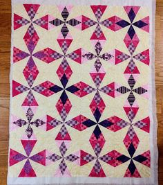 a pink and purple quilt on top of a wooden floor