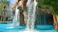 an outdoor swimming pool with waterfall and lounge chairs