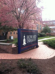 a sign for howard university in front of a tree with pink flowers on it's branches