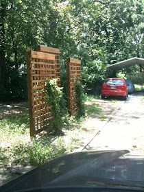 a red car parked in front of a wooden gate on the side of a road