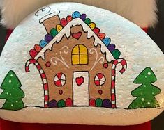 a hand painted rock with a gingerbread house and candy canes on the front