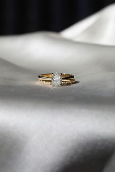 two wedding rings sitting on top of a white cloth