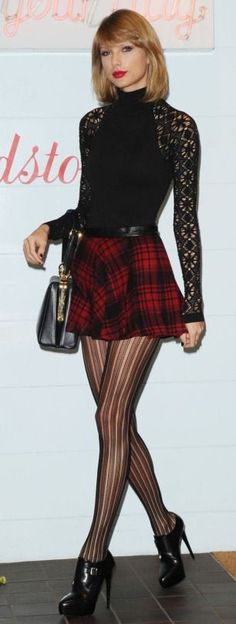 a woman in black top and red plaid skirt