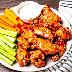 a plate with chicken wings, carrots and celery sticks