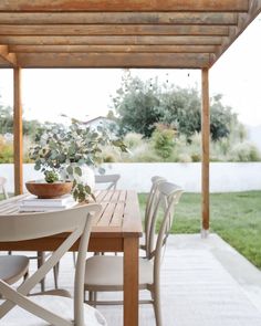 a wooden table with white chairs and a potted plant sitting on top of it