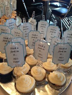 cupcakes with white frosting and blue writing on them sitting on a silver platter