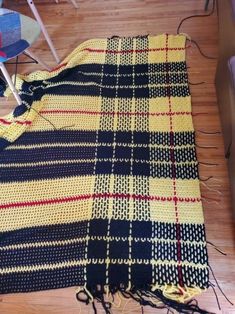 a yellow and black plaid blanket laying on top of a wooden floor next to a chair