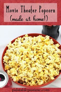 a red bowl filled with popcorn next to a can of soda