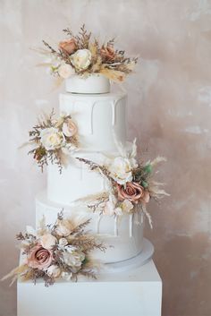 a three tiered white wedding cake with flowers on top