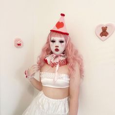 a woman with pink hair wearing a white dress and clown makeup is posing for the camera