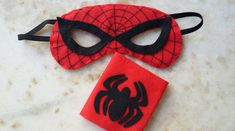 a spiderman mask and red napkin on a white countertop next to a pair of black eye masks