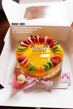 a birthday cake with fruit on top in a box