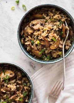 a bowl filled with rice and mushrooms on top of a white tablecloth next to a spoon