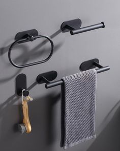 two black towel racks are hanging on the wall next to a pair of toilet brushes