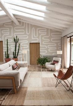 a living room filled with furniture and a large cactus plant on the wall next to it