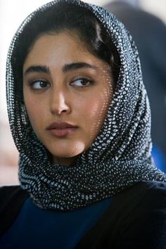 a woman wearing a head scarf and looking at the camera with an intense look on her face