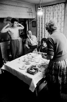 an old black and white photo of people at a table with tea cups on it