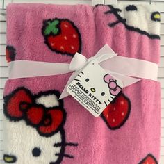 the hello kitty blanket is wrapped in pink and has strawberrys on it's side