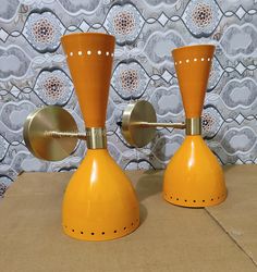 two yellow candlesticks sitting next to each other on top of a cardboard box