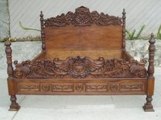 an antique wooden bed frame with intricate carvings on the headboard and foot board, in front of a stone wall