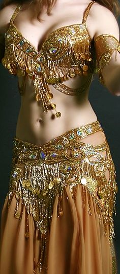 a woman in a belly dance outfit with her hands on her hips and arms behind her head