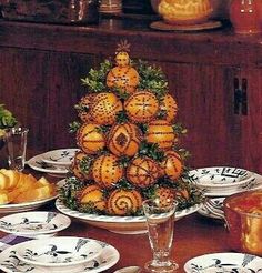 a christmas tree made out of oranges on plates and silverware sitting on a table