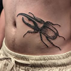 a beetle tattoo on the side of a man's stomach is shown in black ink