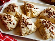 a white plate topped with cookies covered in frosting and pecans on top of a table