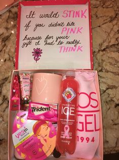 a pink gift box filled with personal care items and a note on the wall behind it