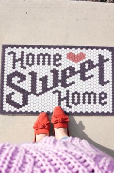 a woman's feet on the ground next to a rug that says home sweet home