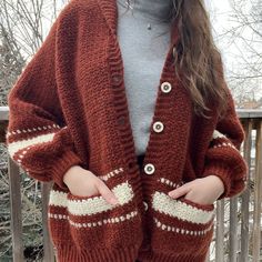 a woman standing on a deck wearing a red and white knitted cardigan sweater