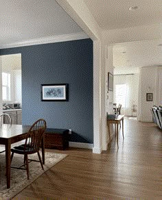 an empty dining room with blue walls and wood flooring is seen in this image