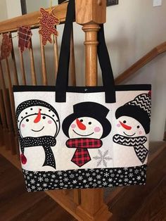 a black and white tote bag with snowmen on it sitting on top of a wooden banister