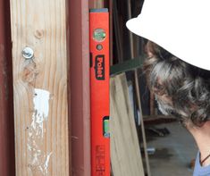 a person with a white hard hat is working on a piece of wood in front of a door