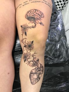 a woman's leg with flowers and a brain tattoo on the side of her thigh