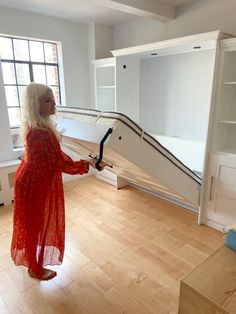 a woman in a red dress is holding a white object and standing on the floor