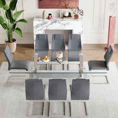 a modern dining table with grey chairs and a white rug on the floor in front of it