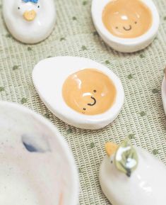 several ceramic animals are sitting on the table next to eggs with faces painted on them