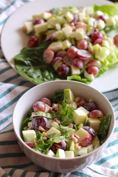 two plates filled with salad on top of a blue and white table cloth next to each other