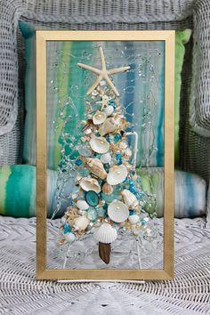 a christmas tree made out of seashells and starfish in a gold frame