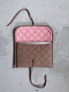 a pink and brown purse sitting on top of a cement floor