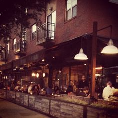 people sitting at tables in front of a restaurant