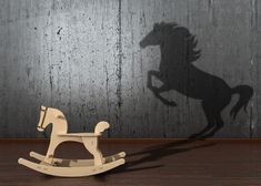 a rocking horse casts a shadow on the wall