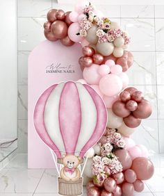 a pink and white balloon with a teddy bear on it is next to some balloons